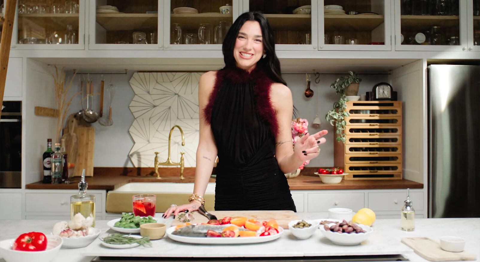 Dua Lipa kookt in een moderne keuken met verse ingrediënten op het aanrecht