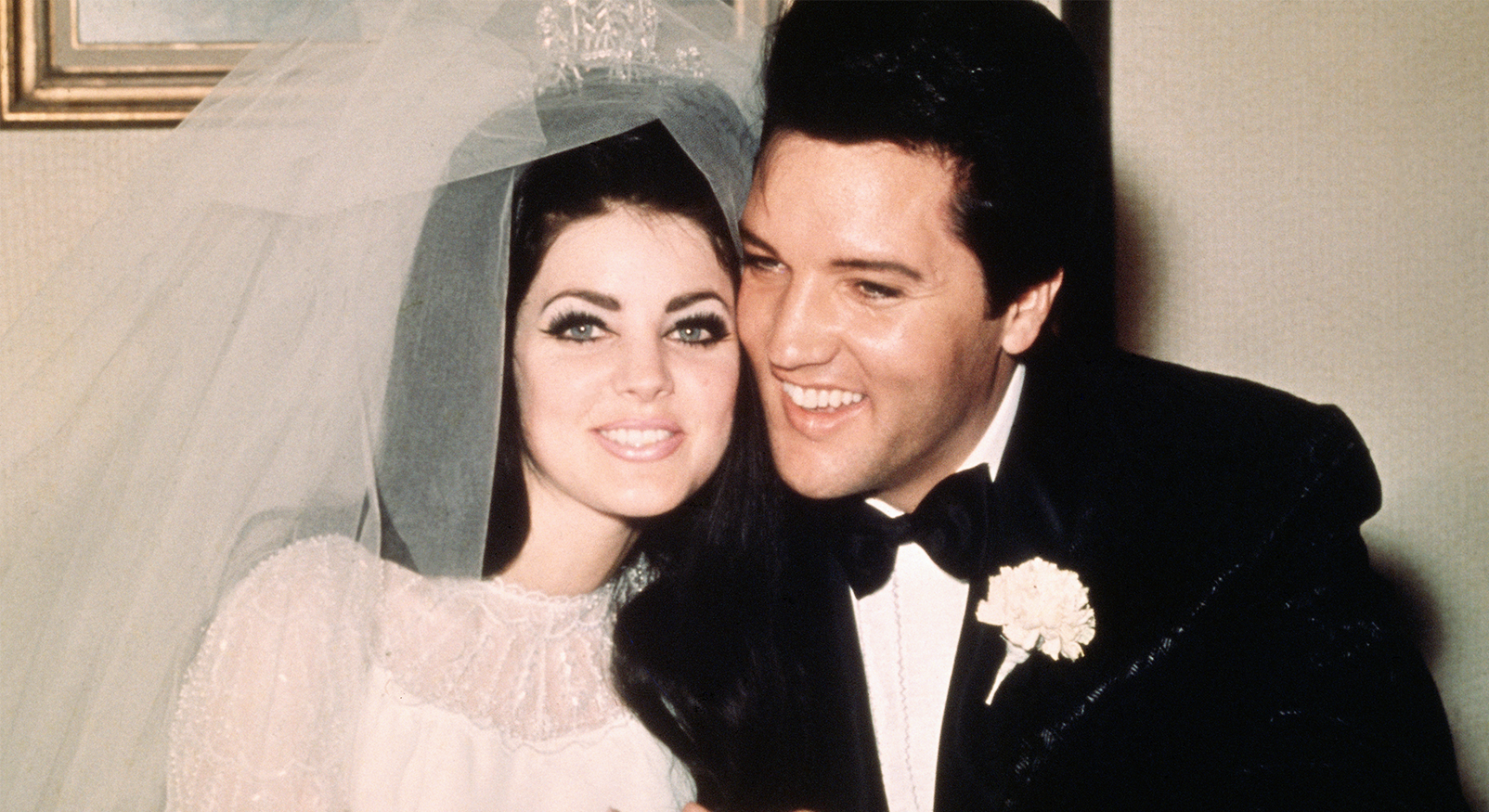 Elvis Presley in smoking naast Priscilla Beaulieu in bruidsjurk en sluier, op hun huwelijksdag in 1967.