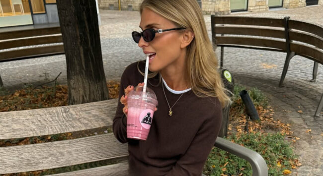 Meisje zit op een bankje met joe and the juice sapje in haar handen