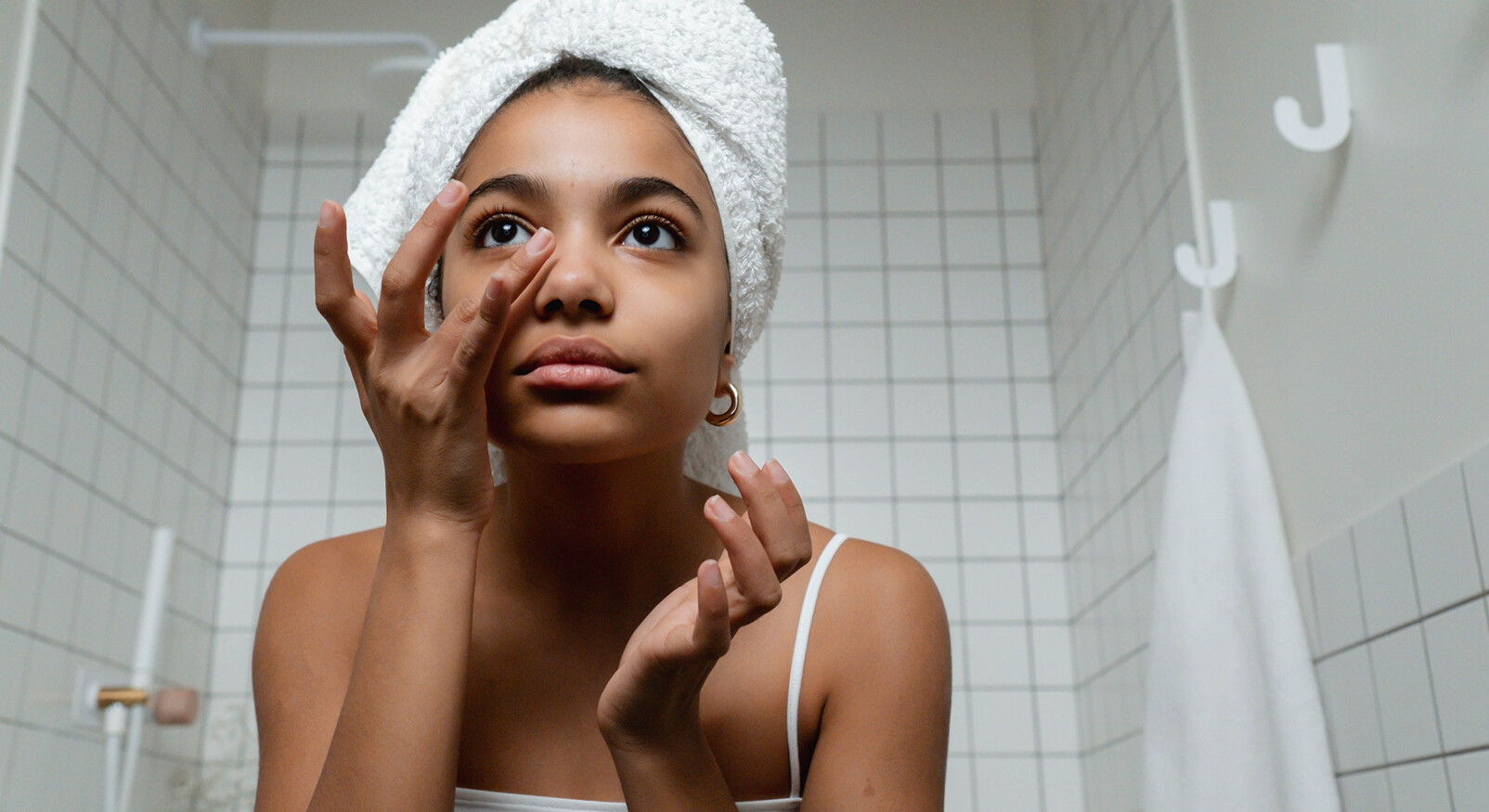 vrouw in de badkamer kijkt naar haar eigen gezicht met handdoek
