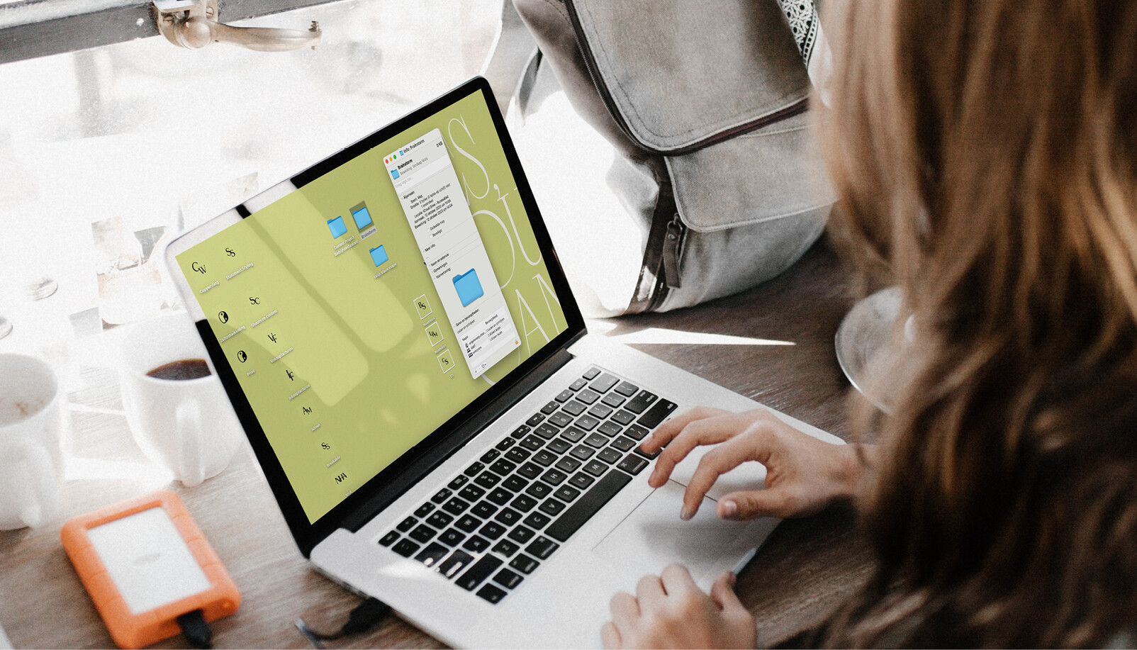 Vrouw achter apple laptop met een groen scherm mapjes maken Finder