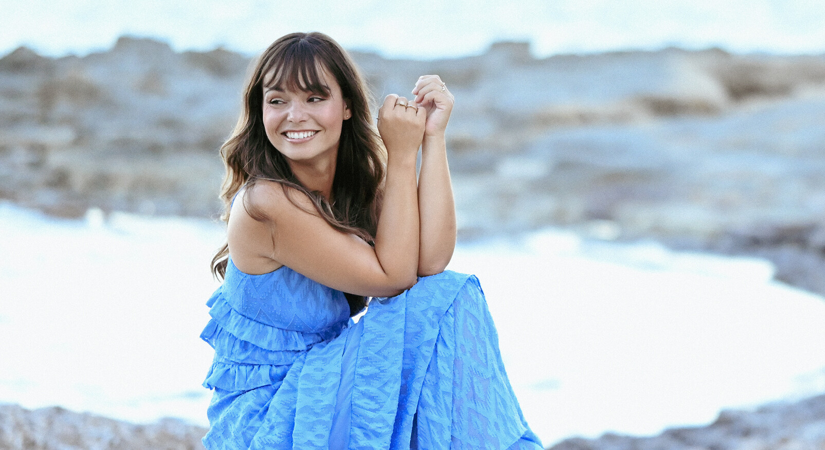 Kiki Duren lachend op het strand in blauwe jurk