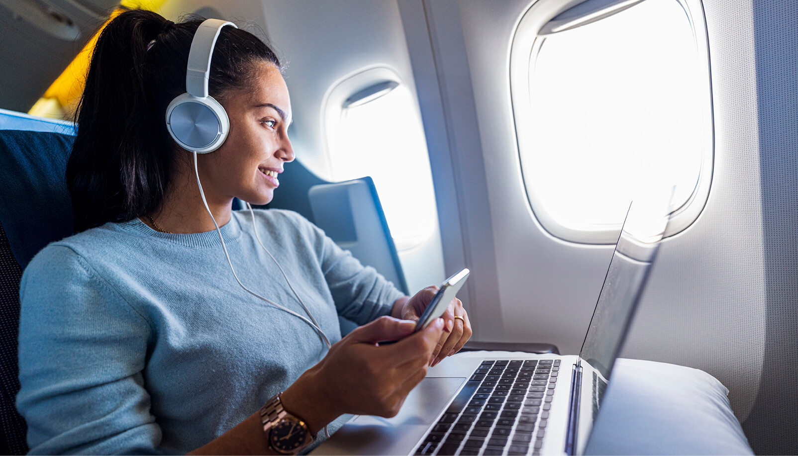 vrouw achter laptop met koptelefoon in het vliegtuig