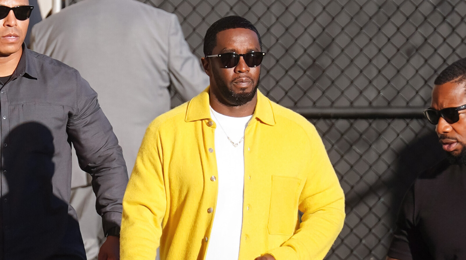 rapper P.Diddy in gele jas op straat lopen met zonnebril