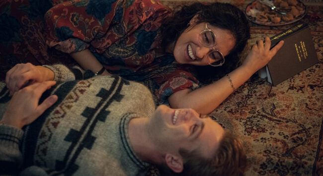Emma en Dexter liggen op de grond en lachen samen in One Day.