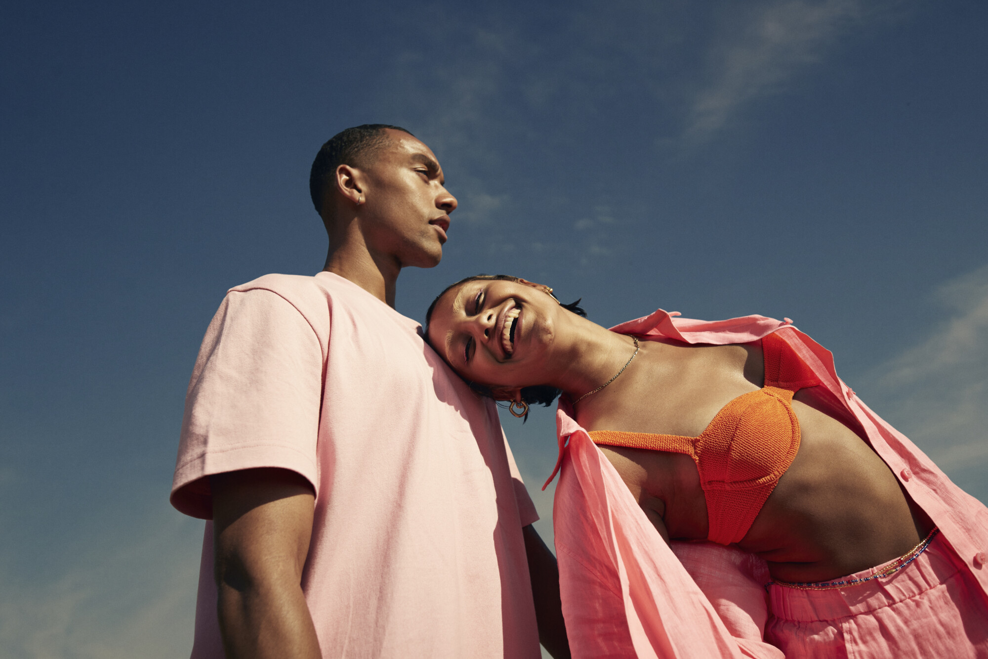 Smiling woman leaning on man against sky