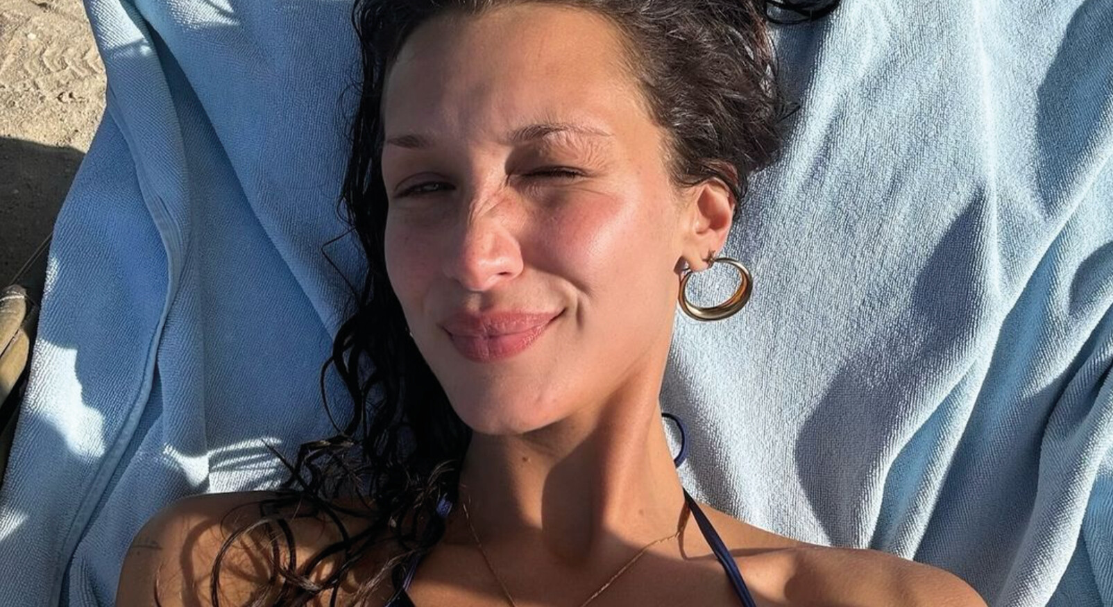 Bella Hadid ligt op het strand liggend in een bikini met nat haar