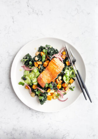 Plate of pan roasted salmon with fresh salad on white background