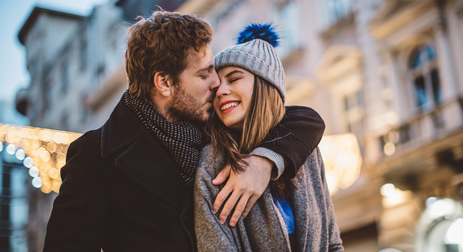 Couple kiss each other lovingly during the holidays in a winter city