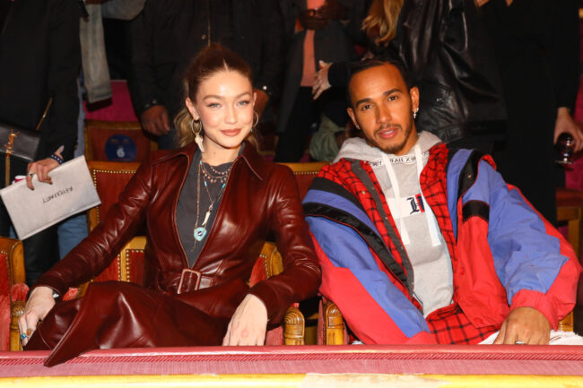  Model Gigi Hadid in leren jas naast Lewis Hamilton in Tommy Hilfiger-jack op een modeshow in 2018.