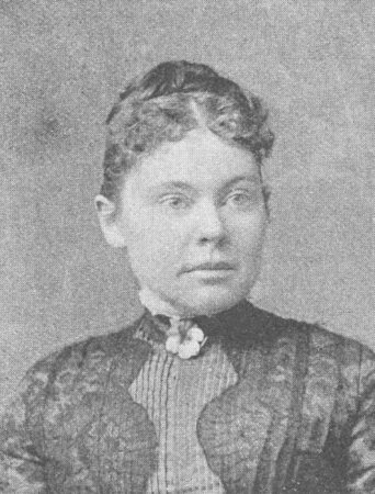 Alt-text for "GettyImages-515508630.jpg":  A historical, grainy, black-and-white photo of American murder suspect Lizzie Borden from the late 19th century. She looks straight ahead. She wears a dark dress or blouse with lace and a high collar with a small light brooch or flower at her neck. Her hair is styled in a formal style of that time.