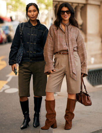 "Twee vrouwen die knielange shorts met hoge laarzen dragen. De vrouw links draagt een donker denim jack over donkergroene shorts en zwarte leren laarzen. De vrouw rechts draagt een oversized geruite blouse met een strik, beige plooishorts en hoge bruine suède laarzen."