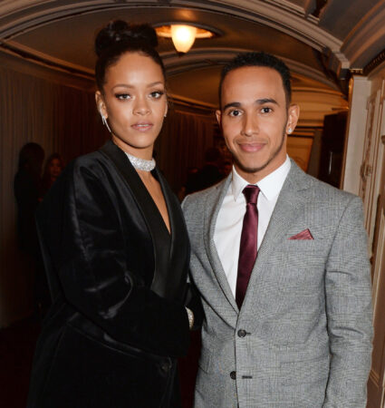 Zangeres Rihanna in zwarte outfit en Formule 1-coureur Lewis Hamilton in geruit grijs pak, poserend op een evenement in 2015.