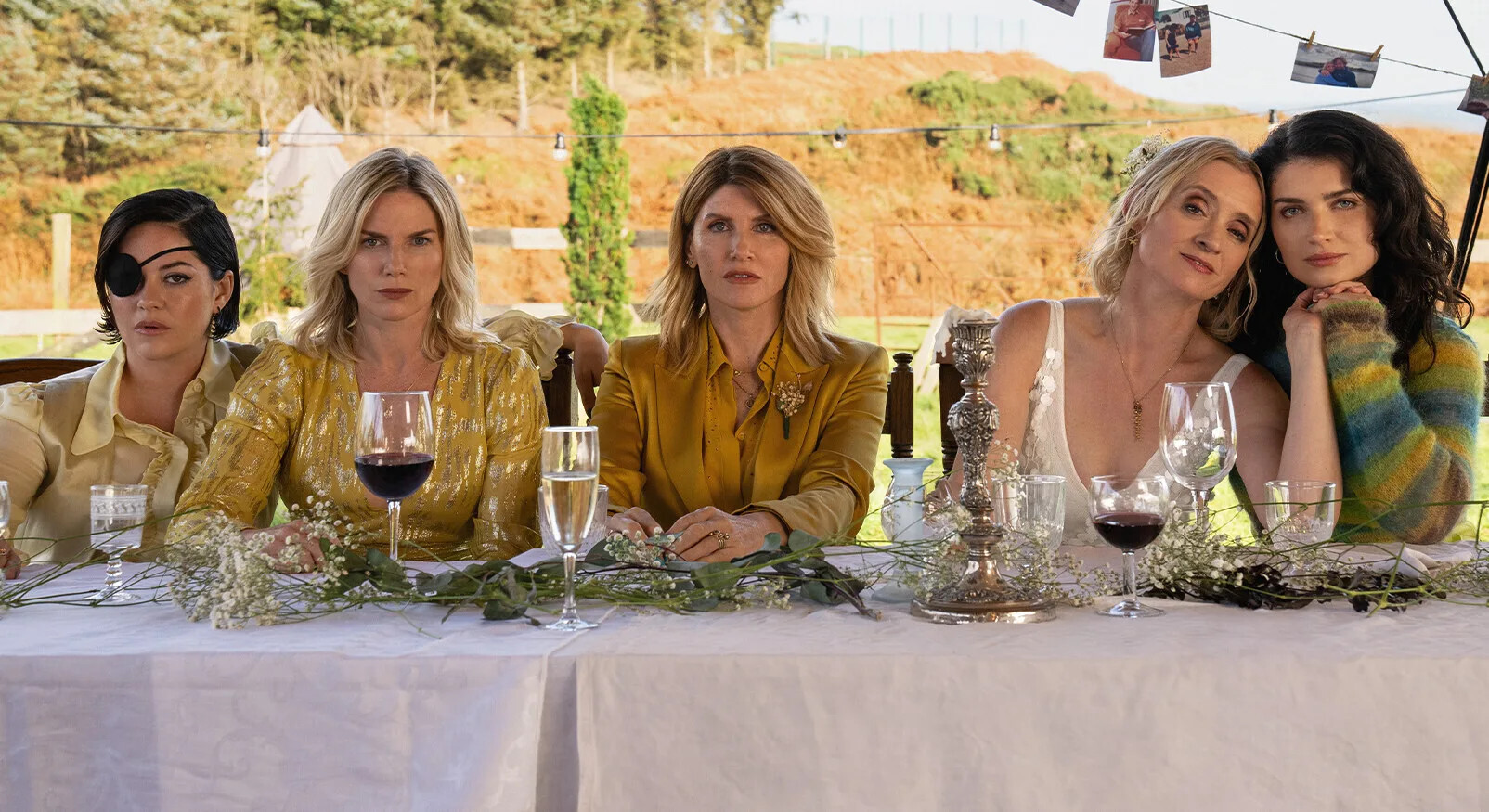 Vijf vrouwen met intense gezichtsuitdrukkingen zitten aan een tafel, wat de sociale strategie en het drama in reality-tv en series illustreert, en uitlegt waarom ons brein hierdoor wordt aangetrokken.
