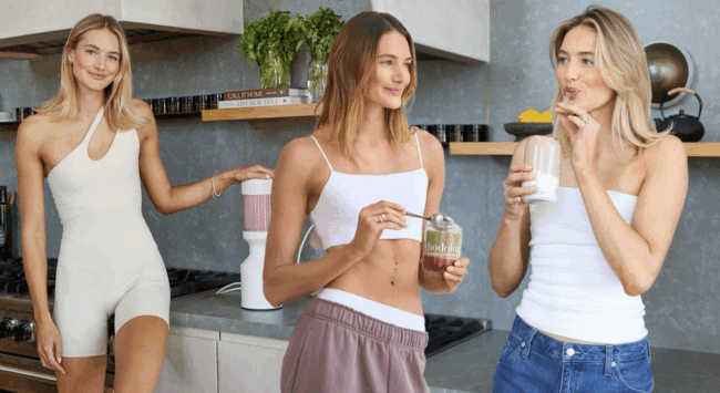 Drie vrouwen bereiden eiwitrijke smoothies en snacks in een moderne keuken met supplementen.