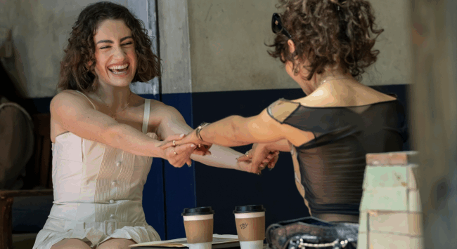 Scène uit de serie 'I Love LA': Maia (Rachel Sennott) en Tallulah (Odessa A’zion) lachen en houden elkaars handen vast.