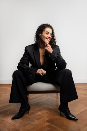 woman with dark curls sitting on a stool