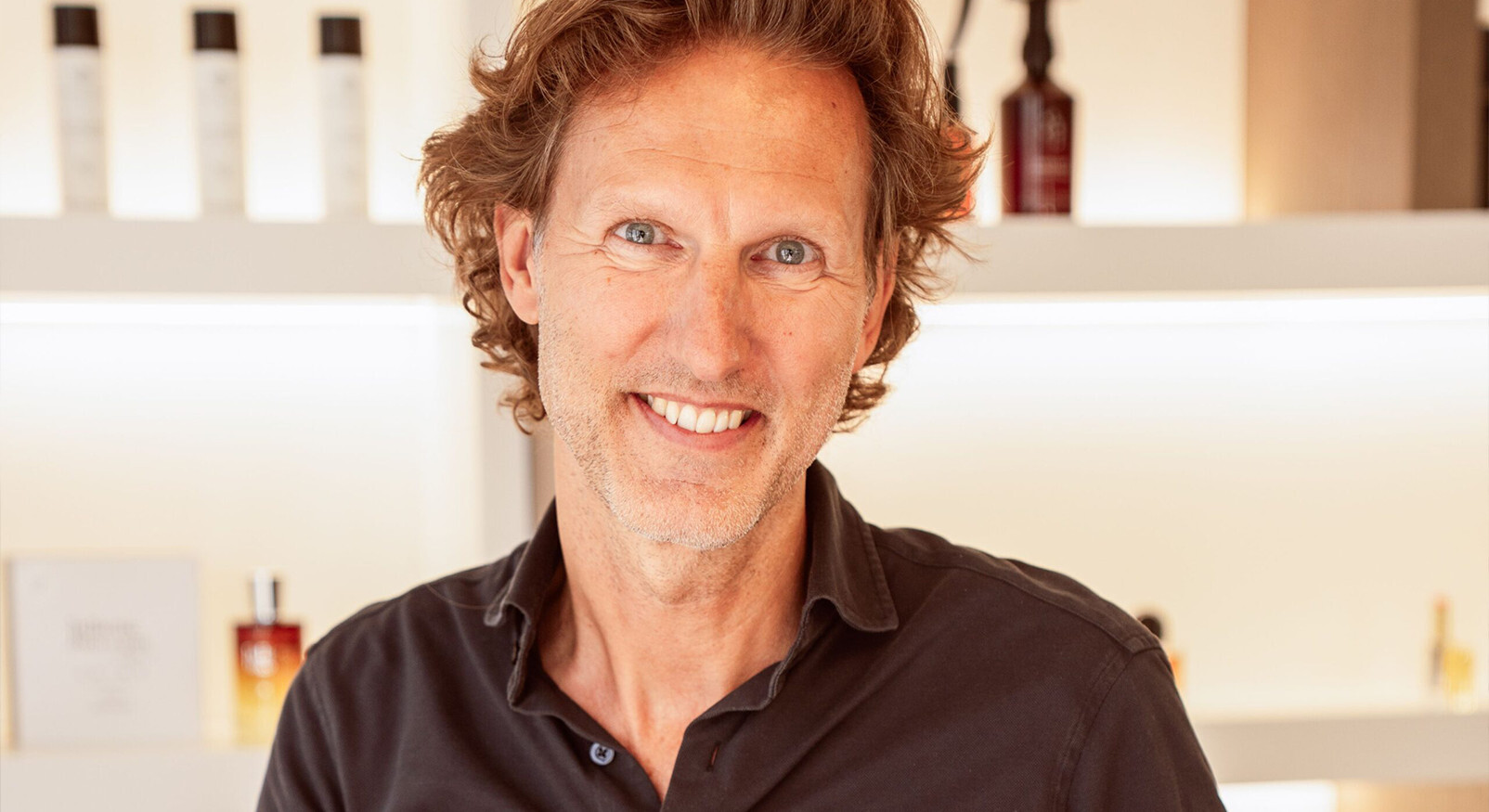 Portret van Philip Hilege, de mede-oprichter van Skins Cosmetics, glimlachend in een van zijn winkels met niche-parfums op de achtergrond.