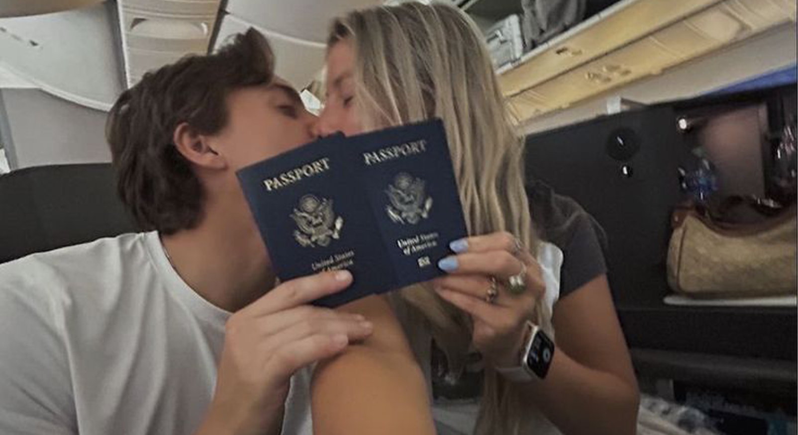 "Koppel in een vliegtuig dat elkaar kust terwijl ze twee Amerikaanse paspoorten voor hun gezicht houden."