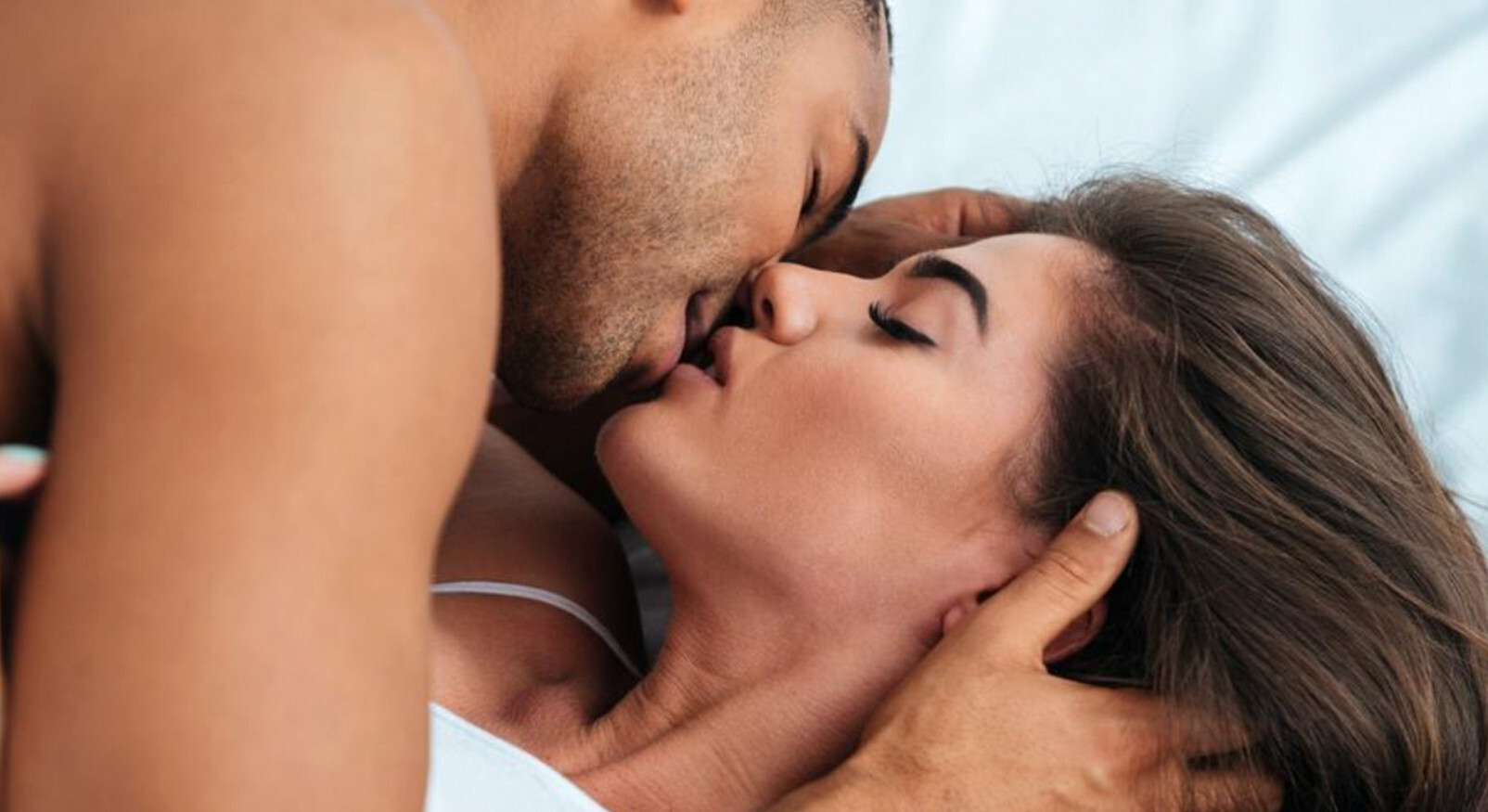 "Close-up van een intiem kussend koppel dat samen in bed ligt."
