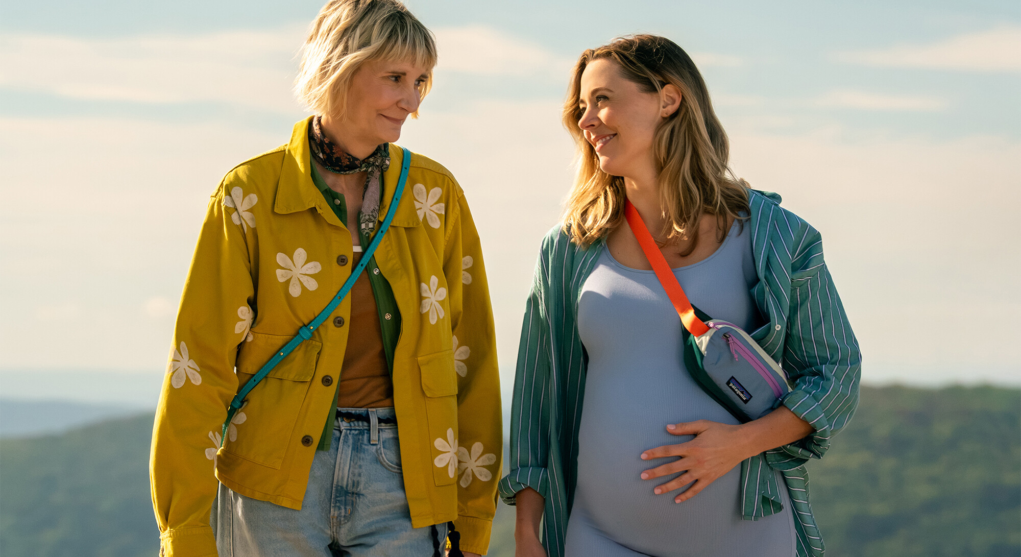 Twee blonde vrouwen voor een lucht met wolken
