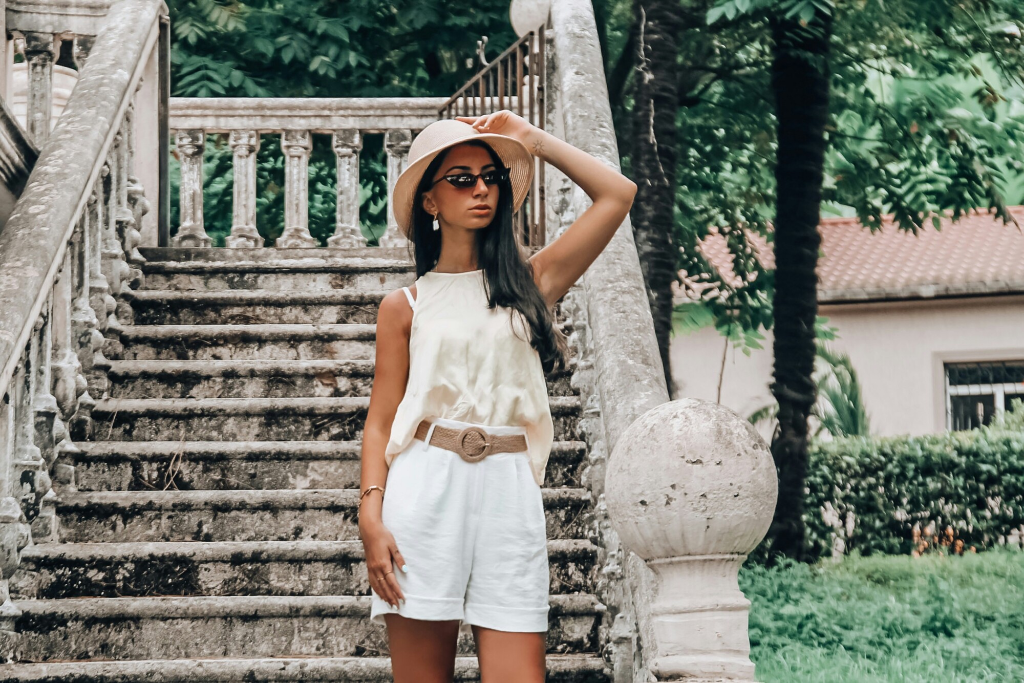Vrouw met zomers wit outfit staat voor een trap