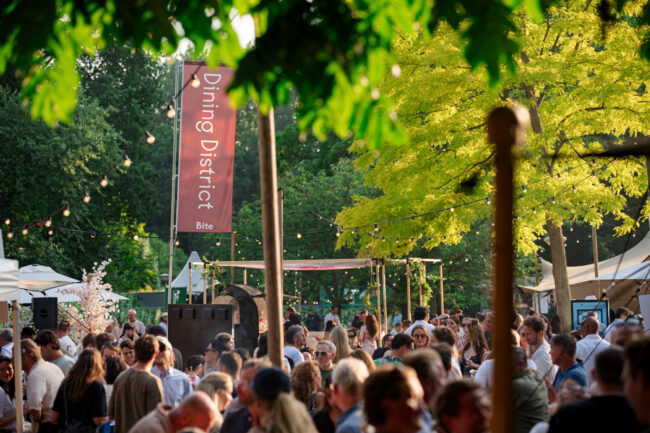 BITE Festival in Amsterdam's Amstelpark with visitors, food stands, lights, and lots of greenery.
