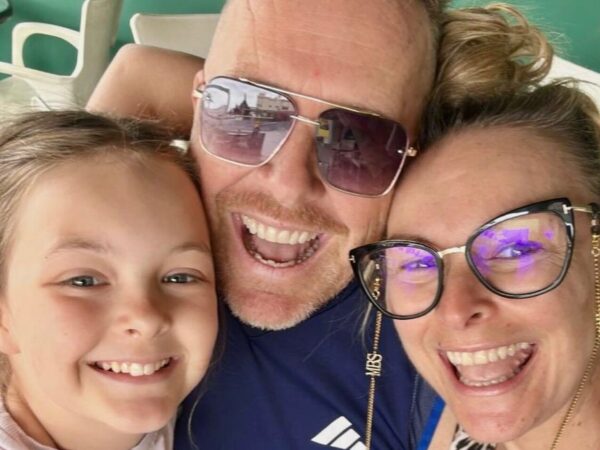 Een vrolijke selfie van drie personen die dicht tegen elkaar aan lachen, onder wie een kind en twee volwassenen met brillen, vermoedelijk op een ontspannen moment samen.