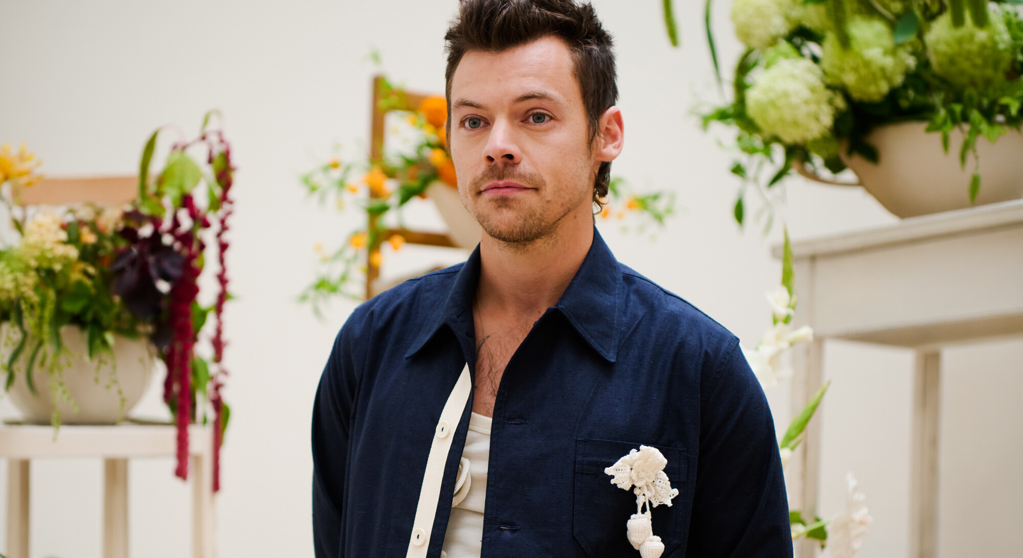 Harry Styles tijdens een promotioneel moment tussen bloemstukken.
