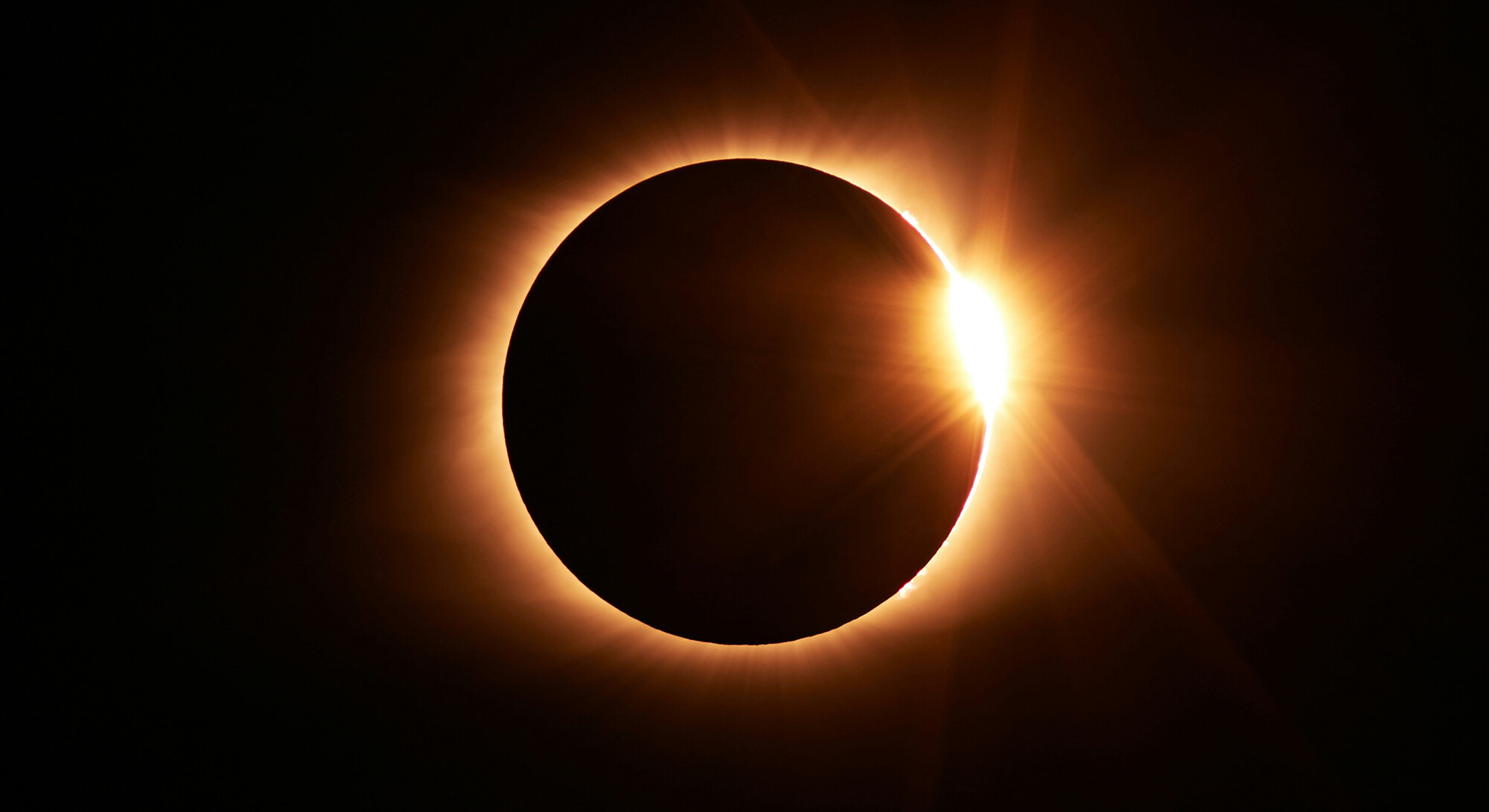 Zonsverduistering met donkere maan voor de zon en fel gouden licht aan de rand.
