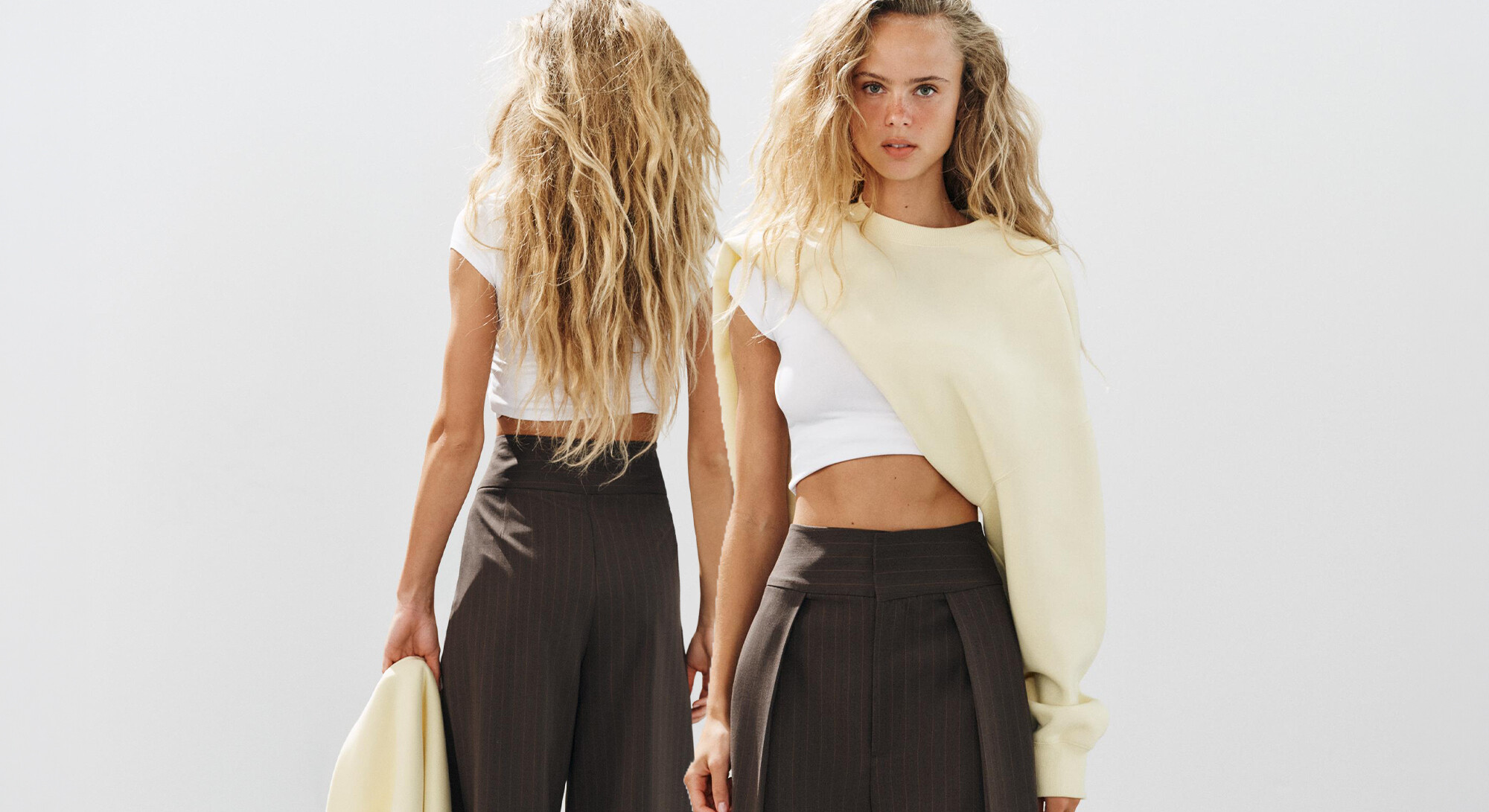Voor- en achteraanzicht van een donkerbruine pantalon met krijtstreep, hoge taille en wijde pijpen, gecombineerd met een witte crop top.
