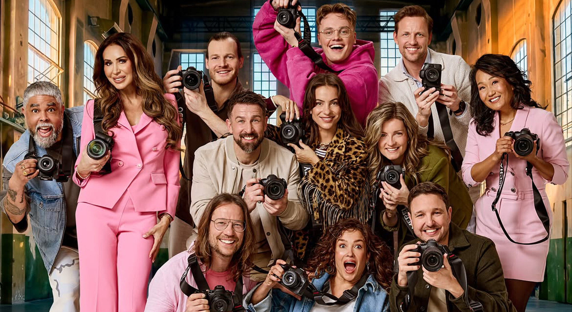 De deelnemers van Het Perfecte Plaatje poseren met camera’s in een industriële hal.