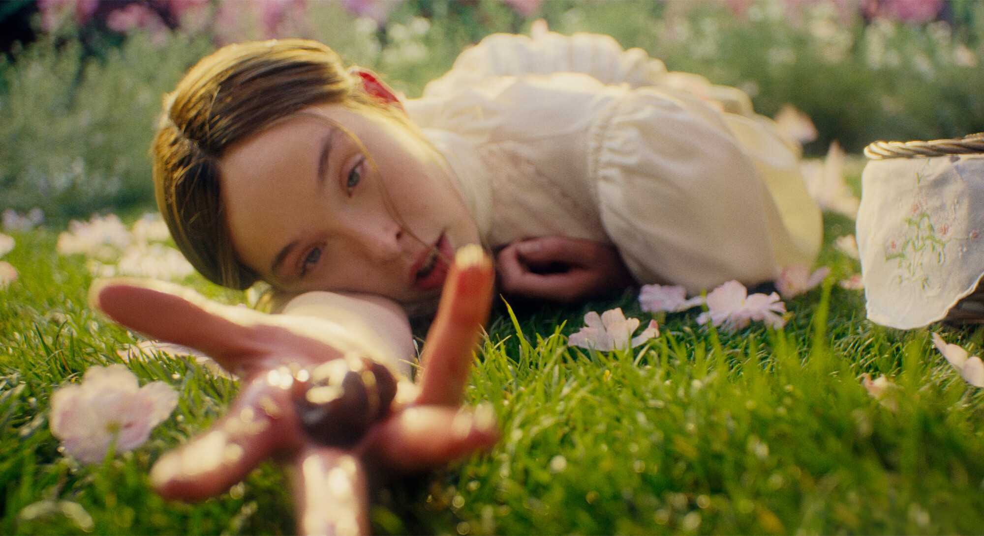 1. Vrouw in witte jurk ligt tussen roze bloemen in het gras in Monster seizoen 4