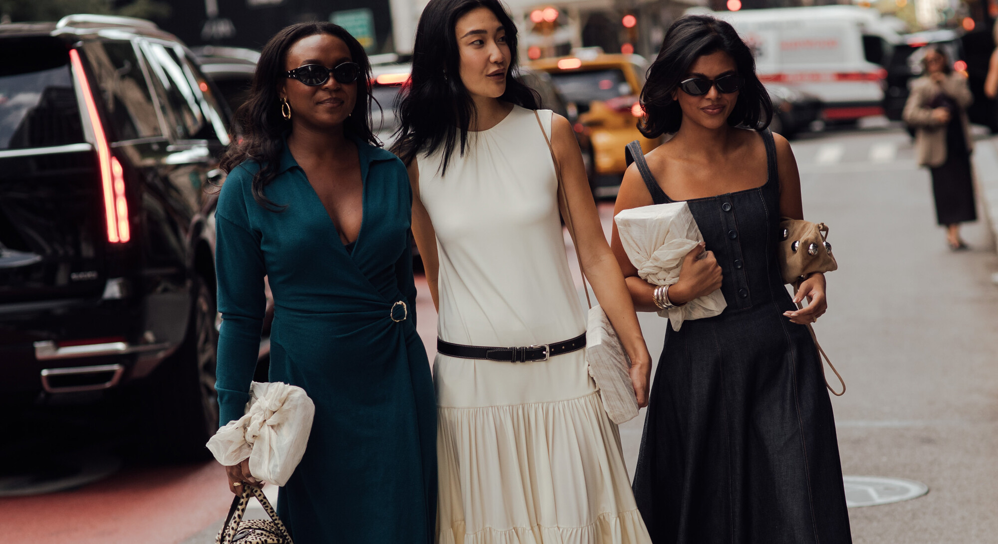 Drie stijlvol geklede vrouwen lopen door de stad tijdens Fashion Week.