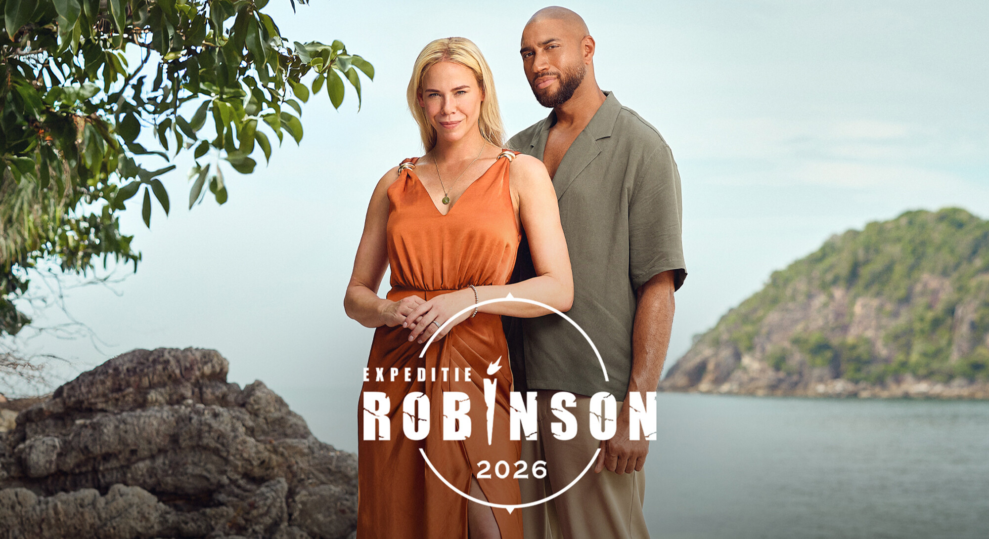 Een vrouw in een oranje jurk en een man in een groen overhemd aan een tropische kust, met het logo van Expeditie Robinson 2026.