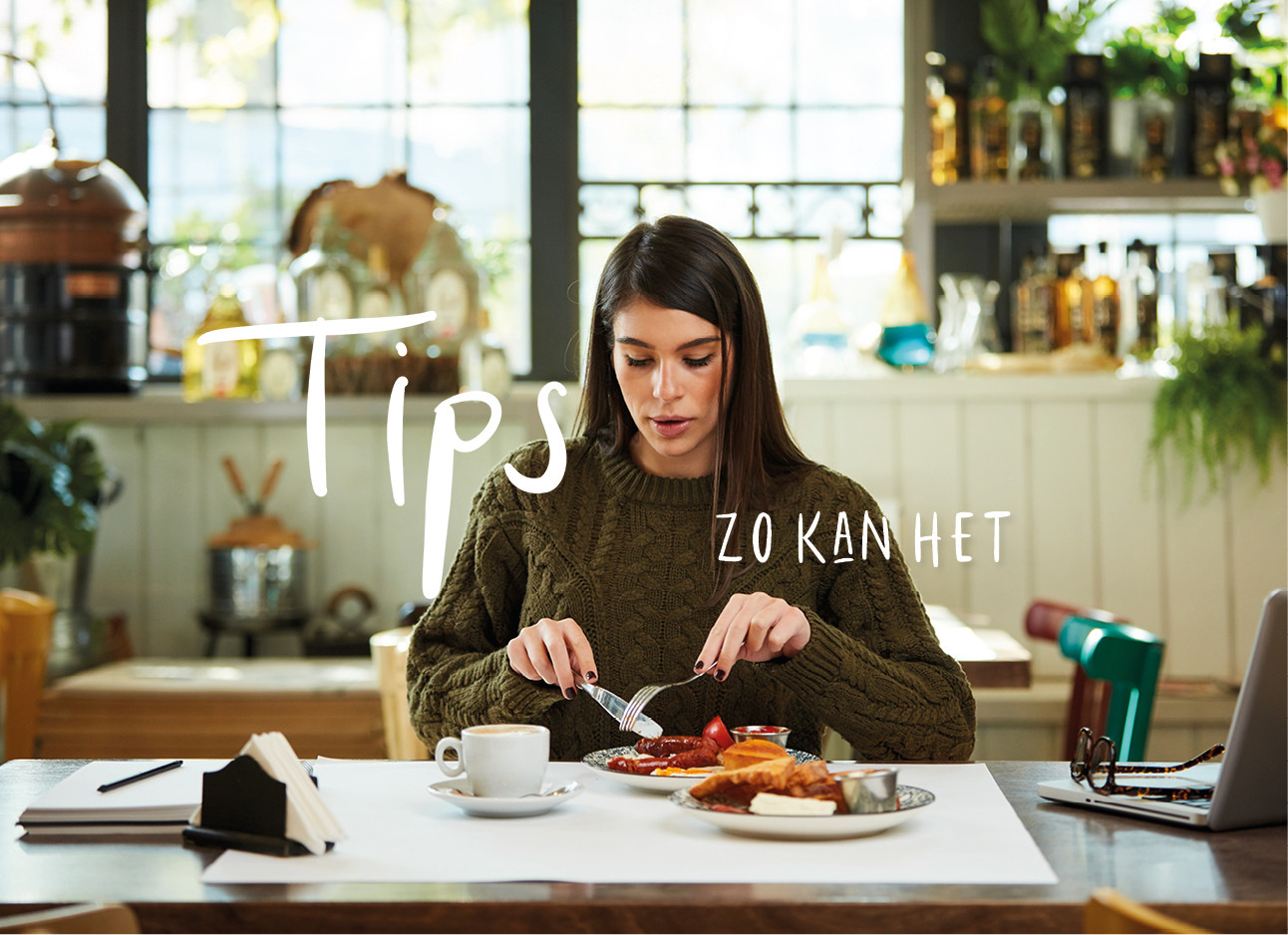 Vrouw eten achter haar laptop met een kop koffie