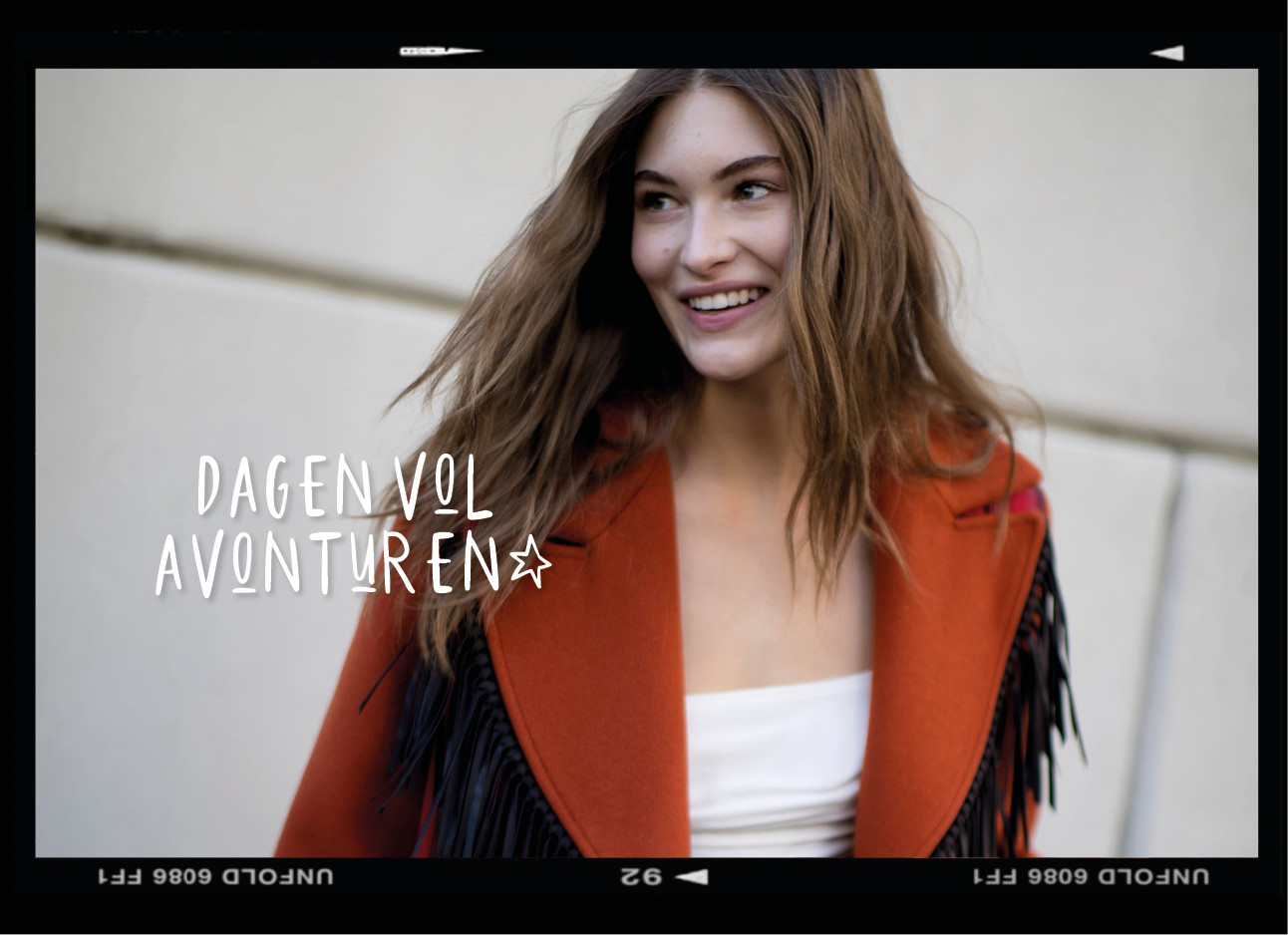 Model op straat lachend met haar haren in de wind