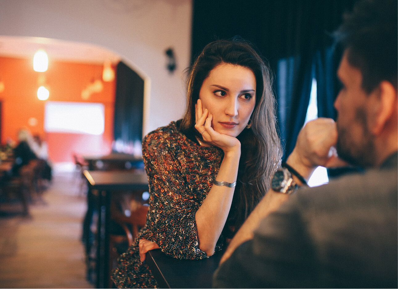 vrouw aan tafel kijkt boos naar een man in restaurant
