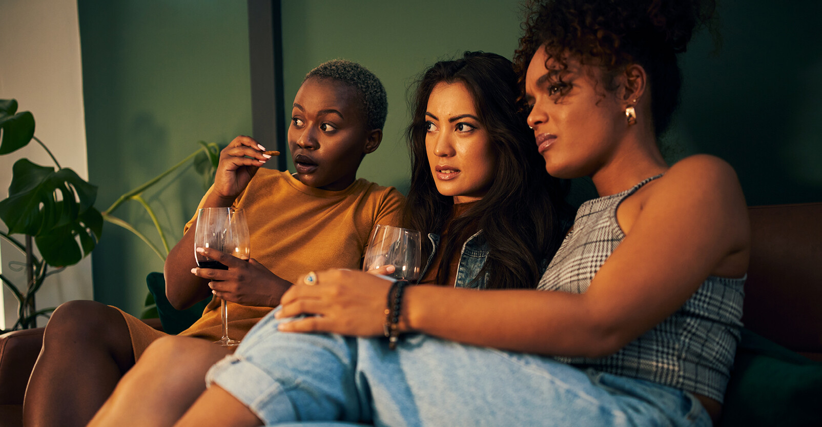 vrouwen op de bank verbaast kijken naar tv scherm popcorm wijn vriendinnen
