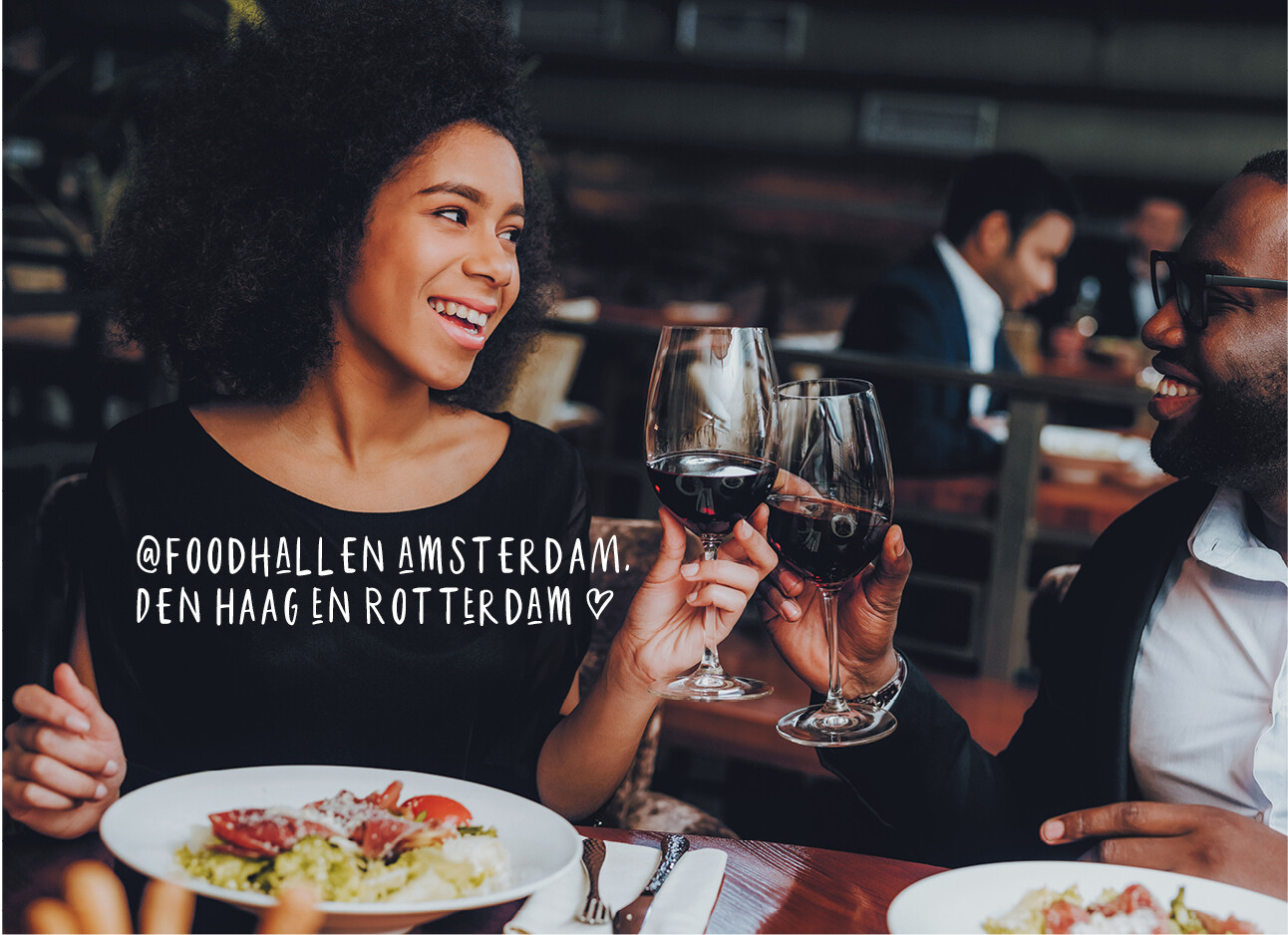 Vrouw en man aan het proosten aan tafel met rode wijn diner