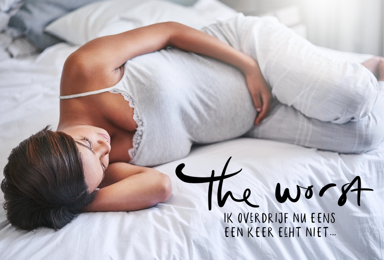 zwangere vrouw ligt op bed in grijs pak