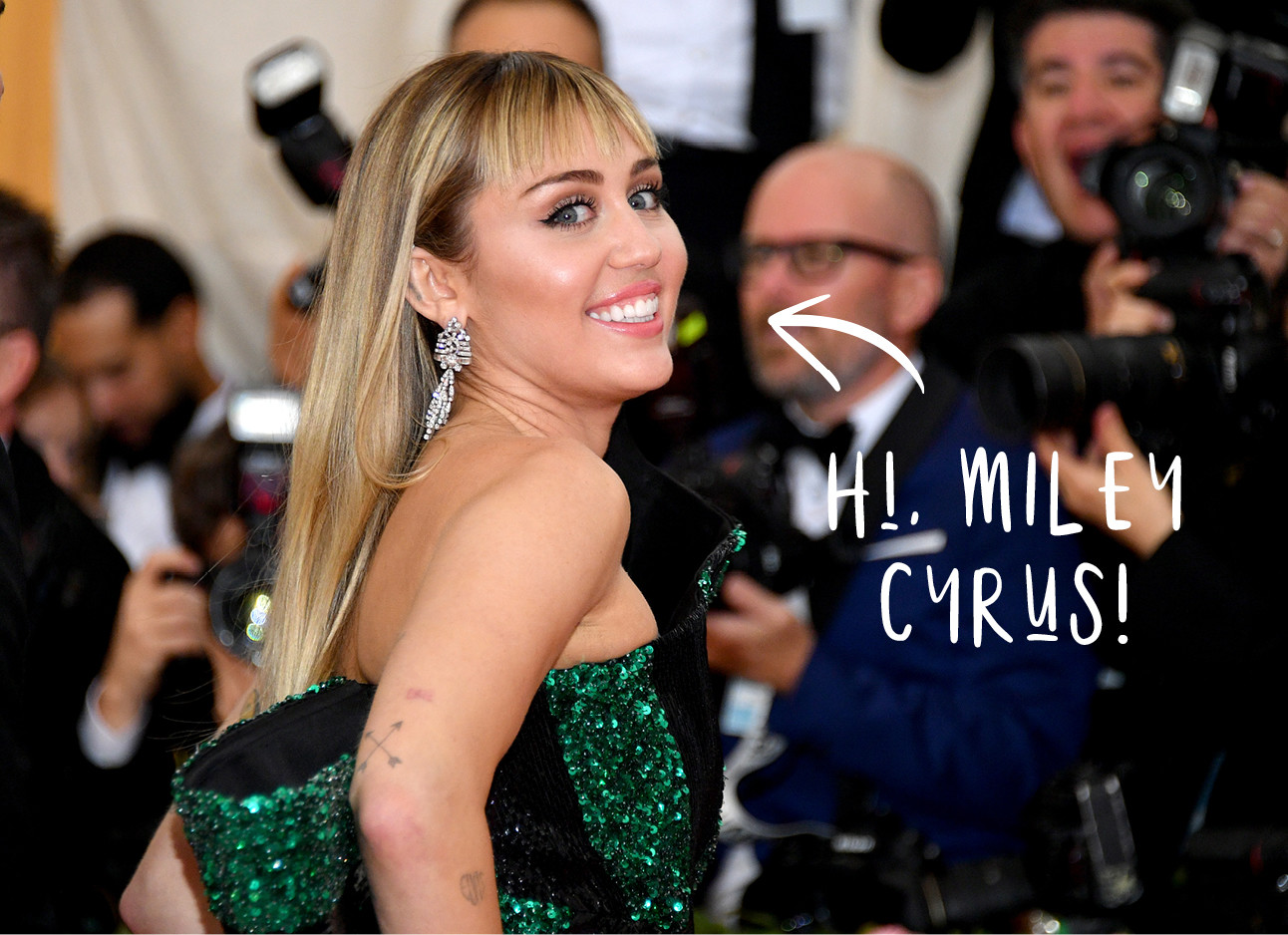 miley cyrus at the met gala in a green & black dress, smiling at the camera's, with blond hair and bangs