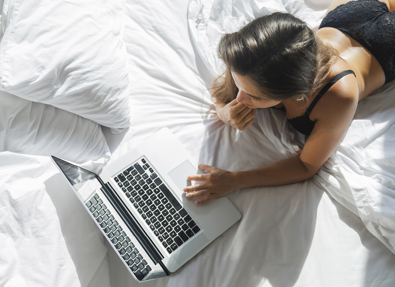 vrouw sexy lingerie achter computer lezen op bed