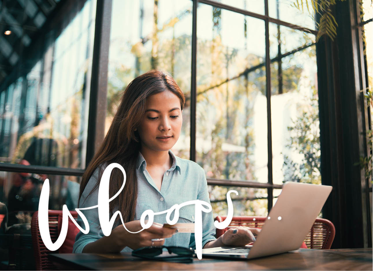 vrouw kijkend naar haar pinpas achter haar laptop winkelen onnline