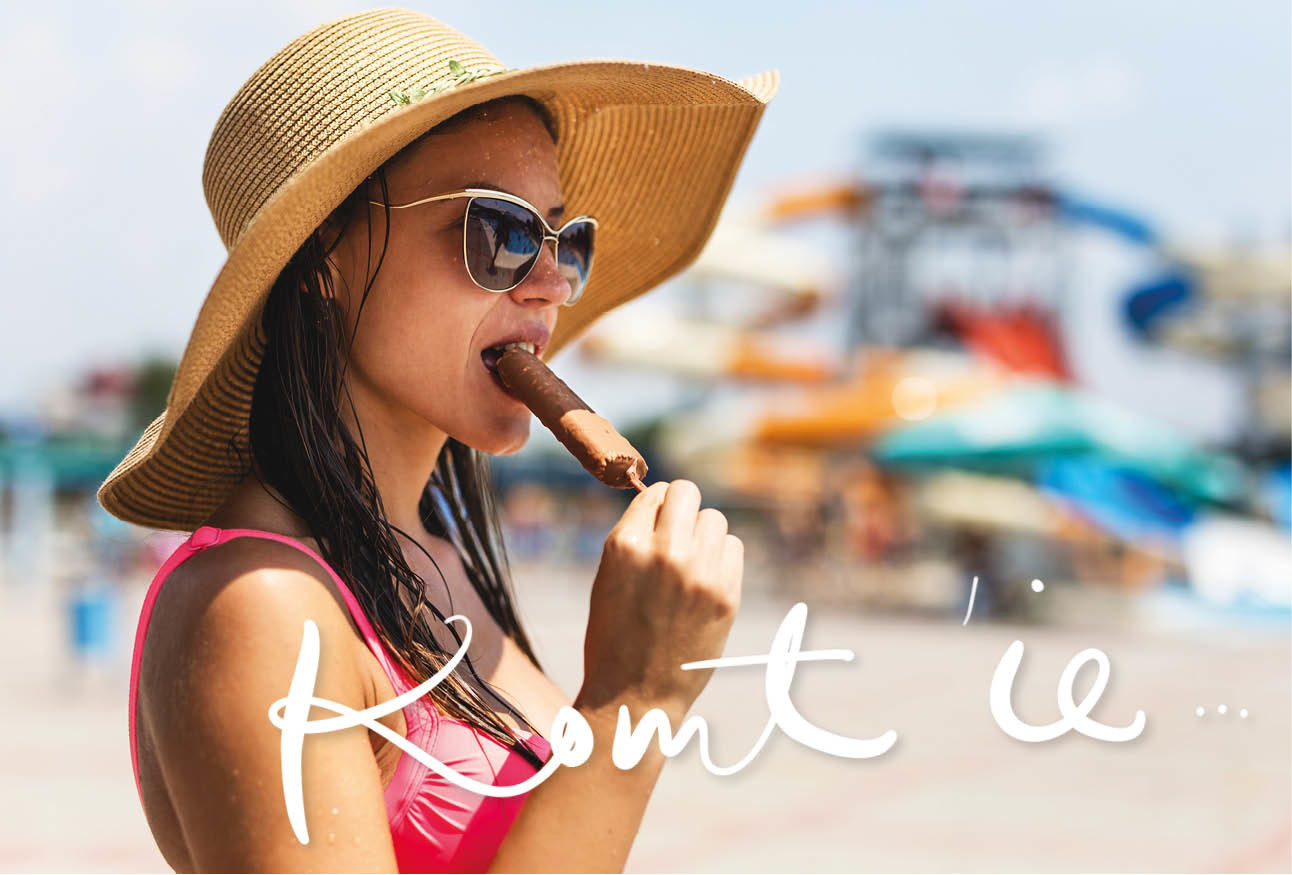 vrouw op het strand met hoed op en ijsje eten