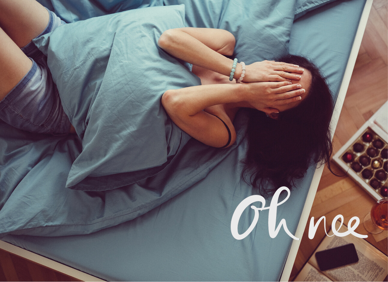 vrouw met handen in het gezicht liggend op bed na een relatiebreuk